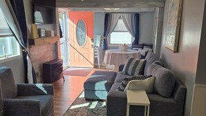 Ein Wohnzimmer mit Sofa, Couchtisch und Deckenventilator. Eine Tür führt in einen anderen Raum.