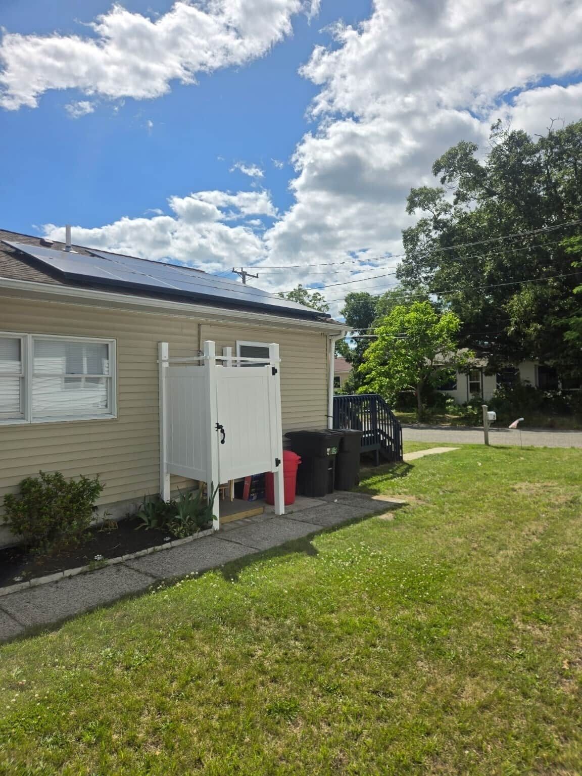 Ein eingeschossiges Haus mit Garage, einem kleinen Garten und einem Baum im Hintergrund.