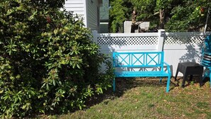 Ein Garten mit einer blauen Bank, einem weißen Zaun und einem Busch.