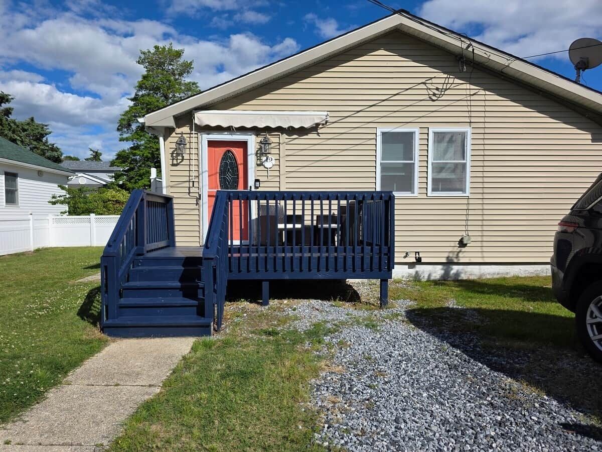 A single-story house with a front porch, a red door, and a satellite dish.