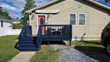 A single-story house with a front porch, a red door, and a satellite dish.