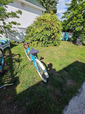 A bicycle parked on a grassy lawn with a white building and a bush in the background. - Barking Bayside Bungalow (Lower Township)