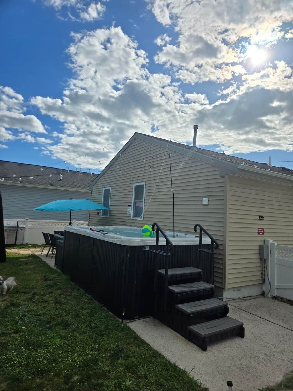 A hot tub with steps leading up to it, a small shed, and a grassy yard.