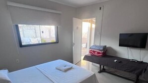 A bedroom with a bed, a television mounted on the wall, and a window. - CITY HOTEL IJUÍ (Ijuí)