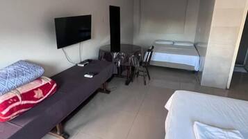 Una habitación de hotel con cama, un escritorio con silla, televisión y ventana.