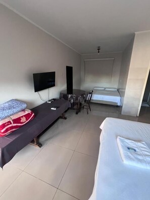A hotel room with a bed, a desk with a chair, a television, and a window. - CITY HOTEL IJUÍ (Ijuí)