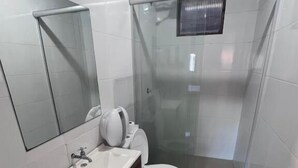 A bathroom with a glass shower enclosure, a toilet, and a sink with a mirror above it. - CITY HOTEL IJUÍ (Ijuí)