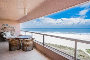 A balcony with a view of the beach, wicker furniture, and a ceiling light fixture. - CBC 2-6D - 2BR/2.5BA Gulf-view condo in Clearwater Beach, on Sand Key. (Clearwater Beach)