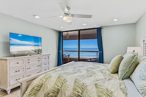 A bedroom with a bed, a TV on a dresser, a ceiling fan, and a view of the beach through large windows. - CBC 2-6D - 2BR/2.5BA Gulf-view condo in Clearwater Beach, on Sand Key. (Clearwater Beach)