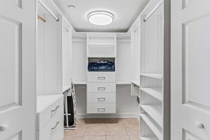 A walk-in closet with white shelving, drawers, and a hanging rack. - CBC 2-6D - 2BR/2.5BA Gulf-view condo in Clearwater Beach, on Sand Key. (Clearwater Beach)