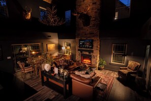 A spacious living room with a fireplace, comfortable seating, and a stone accent wall.