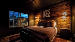 A bedroom with a large window, a bed with a headboard, and two bedside lamps. - Lodge Cabin w/ Hot Tub | 4 Ensuite Kings (Hollister)