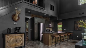 A modern kitchen with a central island, stainless steel appliances, and a rustic wooden cabinet. - Lodge Cabin w/ Hot Tub | 4 Ensuite Kings (Hollister)