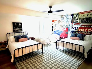 Ein Schlafzimmer mit zwei Etagenbetten aus Metall, einem Deckenventilator und einem Poster an der Wand.