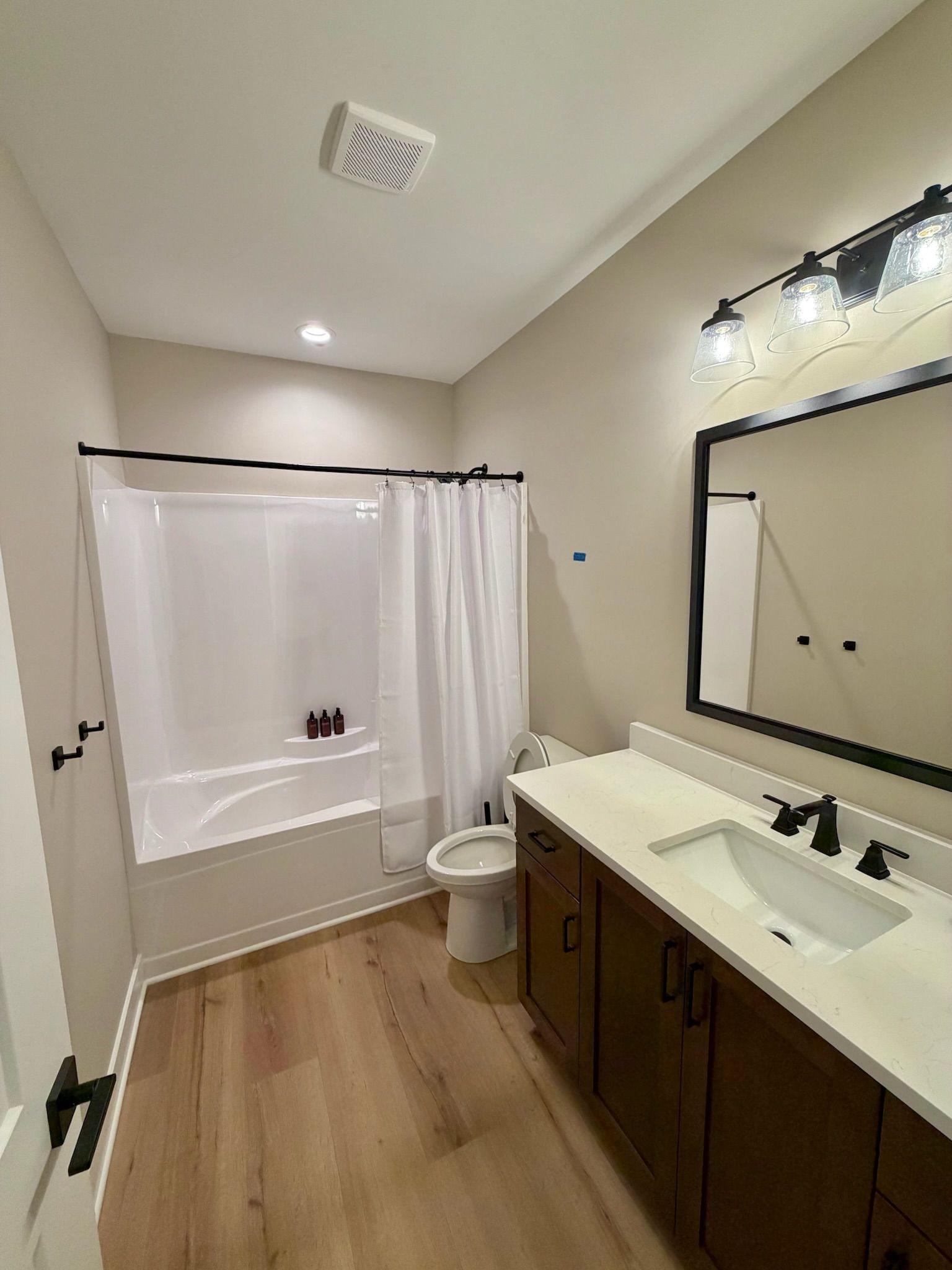 A modern bathroom with a bathtub, toilet, and double sink vanity.