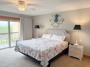 Ein Schlafzimmer mit einem Bett, zwei Nachttischlampen, einem Deckenventilator und einem Wanddekor.