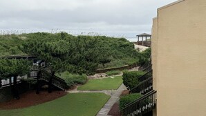A landscaped outdoor area with a wooden deck, a gazebo, and a pathway leading to a grassy lawn. - OBXcitement: Oceanfront Condo, Water Views, Community Pool and Tennis Courts (Nags Head)