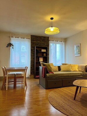 Ein Wohnzimmer mit Esstisch, Sofa und einer Pendelleuchte.