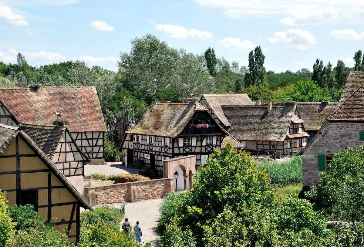 Ein traditionelles Fachwerkhäuschen mit einer Steinmauer und einem Weg, der davorführt.