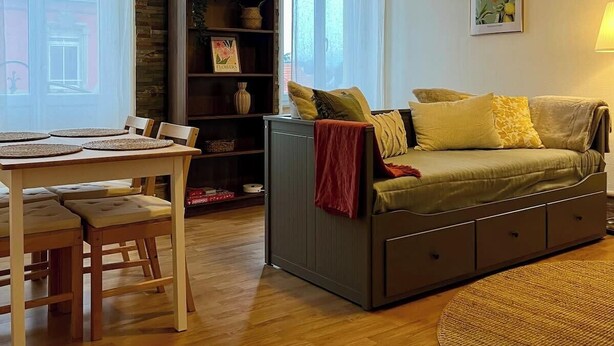 Un salón acogedor con comedor, un sofá, una estantería y una lámpara colgante.