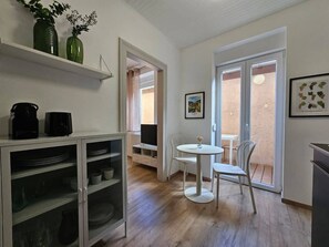 A compact kitchen with a dining area, a TV, and a window with a view. - Studio cocooning à 5km du centre de Strasbourg (Schiltigheim)