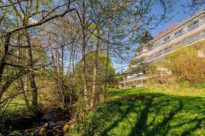 Un edificio residencial con un sendero que lleva a una zona verde, rodeado de árboles y vegetación.