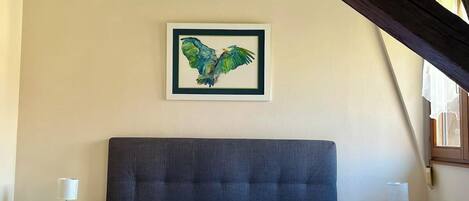 Un dormitorio con una cama grande, un cuadro enmarcado en la pared y una ventana con cortinas.