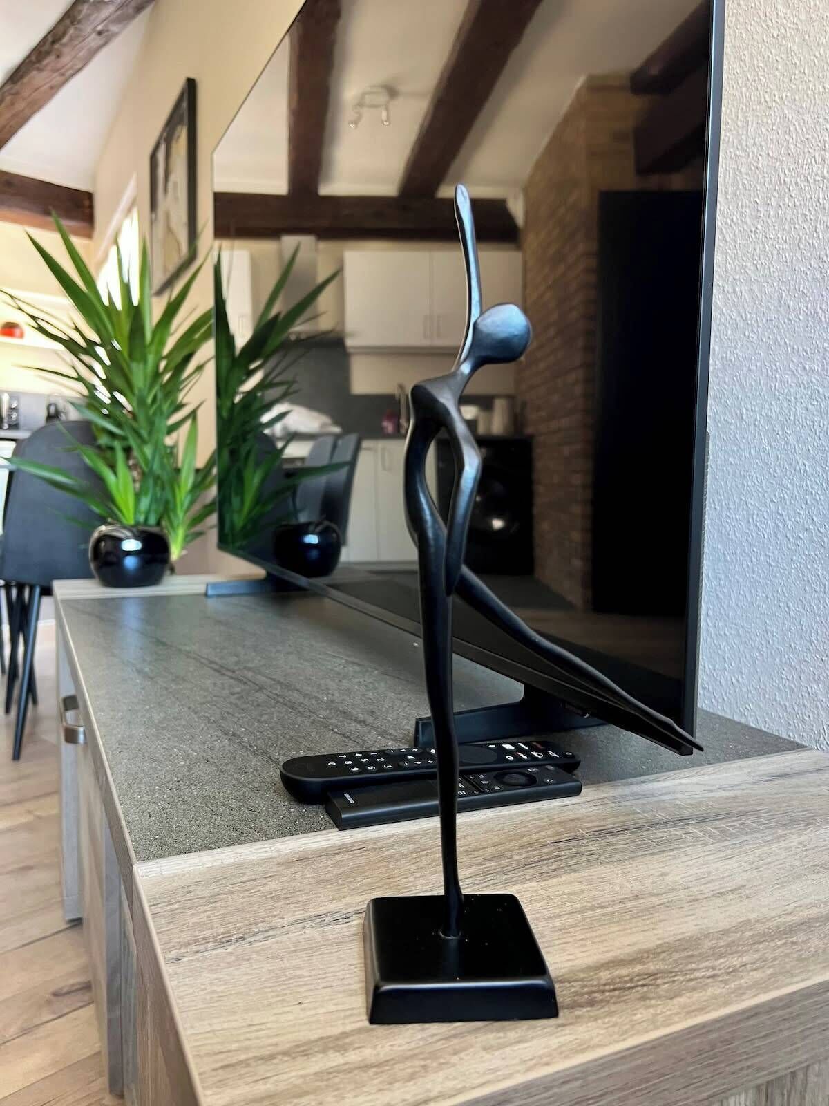 A modern kitchen with a wooden countertop, a black sculpture, and a laptop.