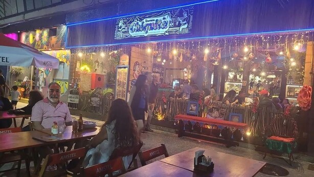 An outdoor dining area with tables and chairs, a neon sign, and decorative lights. - 2 min da Praia de Copacabana - Reformado (Rio de Janeiro)