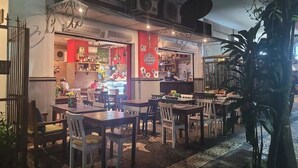 An outdoor dining area with tables and chairs, a bar area with a counter, and a large potted plant. - 2 min da Praia de Copacabana - Reformado (Rio de Janeiro)