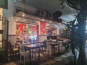 An outdoor dining area with tables and chairs, a bar area with a counter, and a large potted plant. - 2 min da Praia de Copacabana - Reformado (Rio de Janeiro)