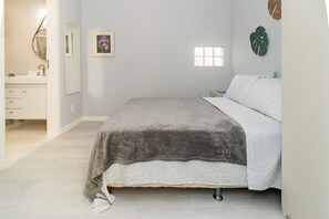 A bedroom with a bed, a nightstand, a dresser, a window, and a wall-mounted mirror. - 2 min da Praia de Copacabana - Reformado (Rio de Janeiro)
