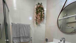 A bathroom with a shower, toilet, and a sink with a mirror. - 2 min da Praia de Copacabana - Reformado (Rio de Janeiro)