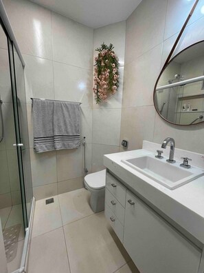 A bathroom with a shower, toilet, and a sink with a mirror. - 2 min da Praia de Copacabana - Reformado (Rio de Janeiro)