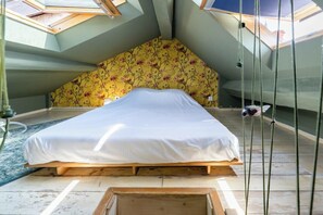 A room with a bed, skylight, and a floral-patterned wall. - Beautiful apartment in the heart of Annecy (Annecy)