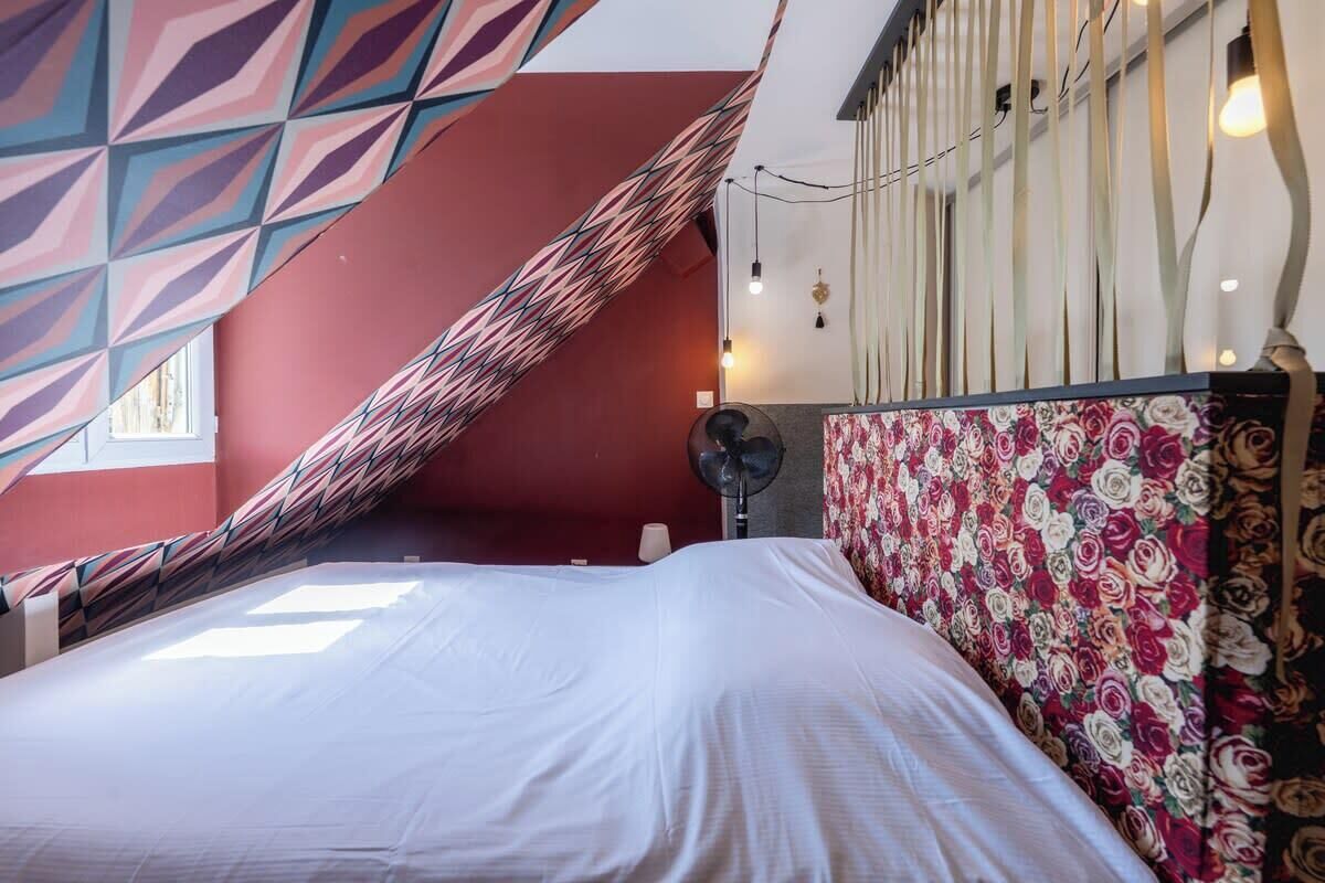 A room with a bed, a patterned wall, and a fan.