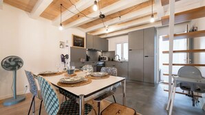 Una cocina moderna con comedor, vigas de madera en el techo y un ventilador.
