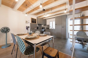 A modern kitchen with a dining area, wooden ceiling beams, and a fan. - Beautiful apartment in the heart of Annecy (Annecy)