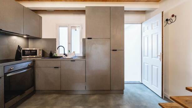 Una cocina moderna con electrodomésticos integrados, techo de madera y vistas al exterior.