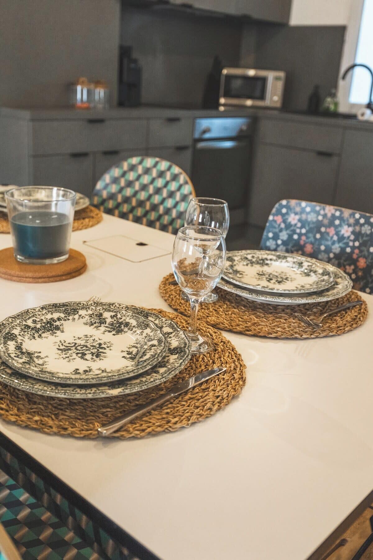 A dining table set with plates, a glass of water, and a wine glass.