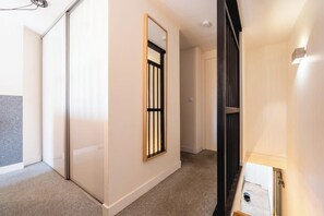 A hallway with a sliding door, a framed window with a black grille, and a light fixture on the wall. - Beautiful apartment in the heart of Annecy (Annecy)
