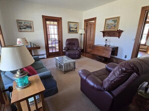 Ein Wohnzimmer mit Sofa, Sessel, Couchtisch, Lampe und Bildern an der Wand.