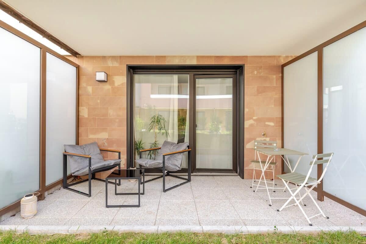 Een balkon met twee stoelen, een tafel en een glazen schuifdeur.
