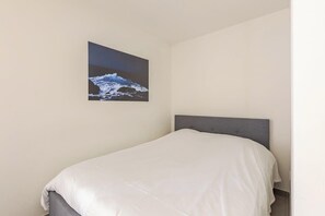 A single bed with a grey headboard in a room with plain walls.