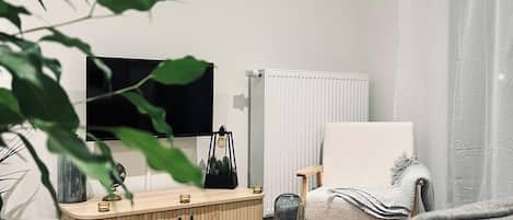 Een moderne woonkamer met een bank, een ronde salontafel, een televisie en een radiator.