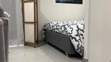 Een slaapkamer met een bed, een nachtkastje, een aan de muur hangend schilderij en een deur.