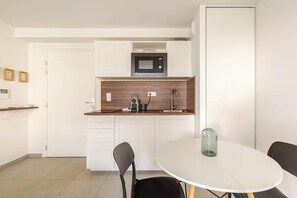 A compact kitchen with a microwave, sink, and a small dining table with chairs.