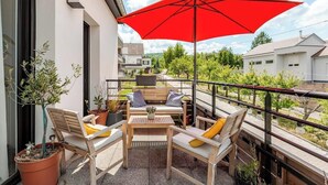 A balcony with outdoor furniture, a red umbrella, and potted plants. - Cozy T2 (1-bedroom) with vineyard view (Rosheim)