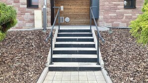 A set of outdoor stairs leading to a building entrance with a stone facade and a wooden panel wall. - Cozy T2 (1-bedroom) with vineyard view (Rosheim)