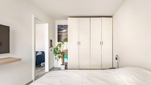 A bedroom with a bed, a wardrobe, a potted plant, and a wall-mounted TV. - Cozy T2 (1-bedroom) with vineyard view (Rosheim)